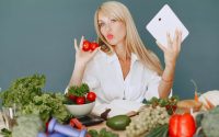 Vlogger promoting healthy eating with fresh vegetables on the table.