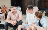 Family sharing quality time on a wooden terrace. Smiling and conversing.